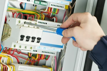 Elektrikář upravuje rozvaděč s barevnými vodiči.