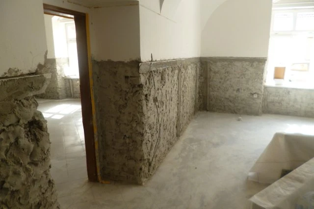 Stěny s nanášenou sanační omítka v interiéru během stavebních prací.