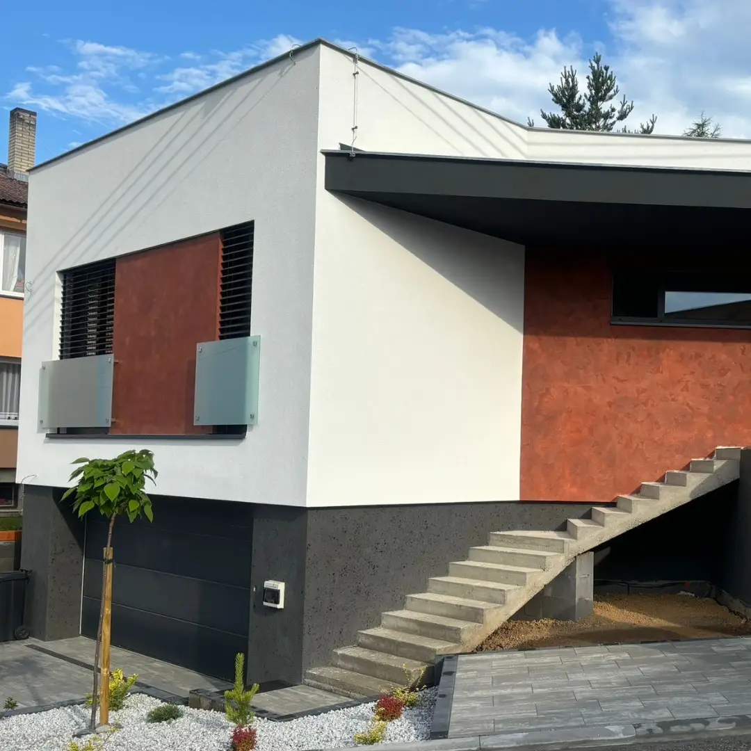 Moderní dům s pohledovým betonem na schodišti a spodní fasádě.