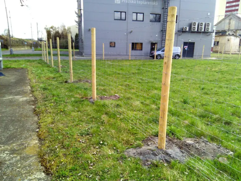 Nová dřevěná plotová konstrukce s drátovým pletivem na trávníku.
