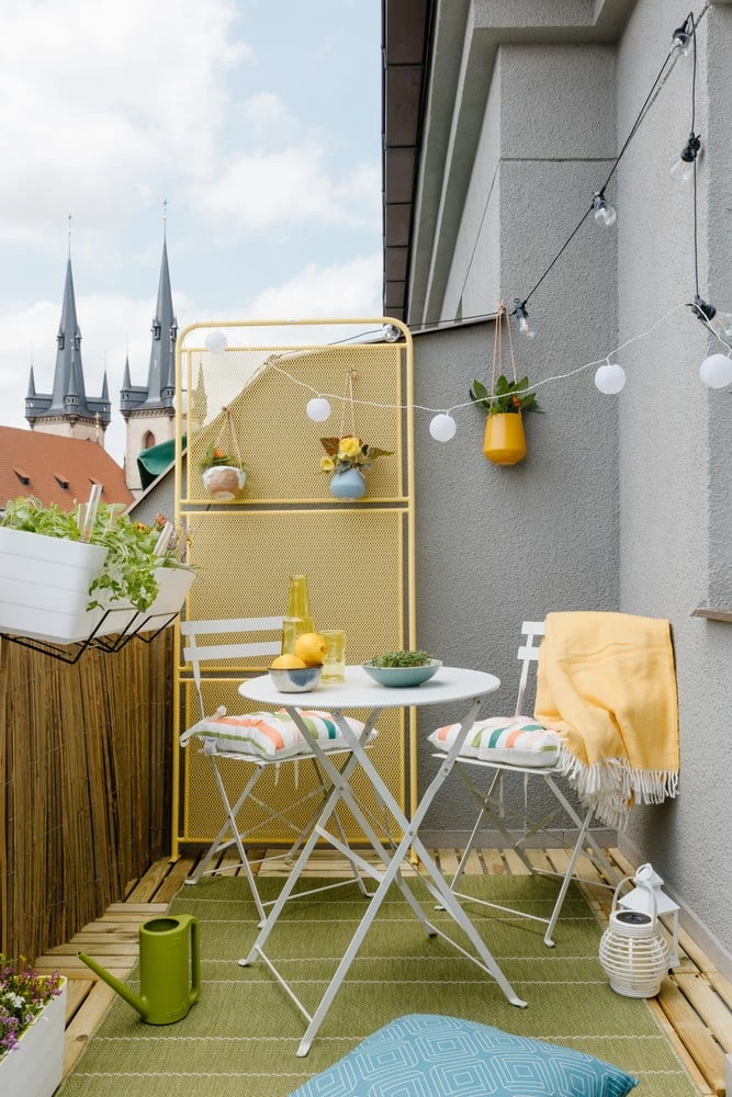 Ukázka útulné balkónové terasy s rostlinami a žlutým nábytkem.