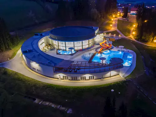 Noční pohled na osvětlené bazénové centrum s vodními skluzavkami.