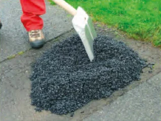 Pracovník rozšiřuje tekutý asfalt lopatou na povrchu.
