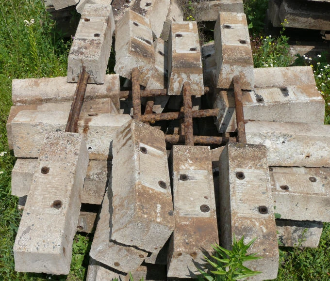 Staré betonové pražce s výztuží ležící venku.
