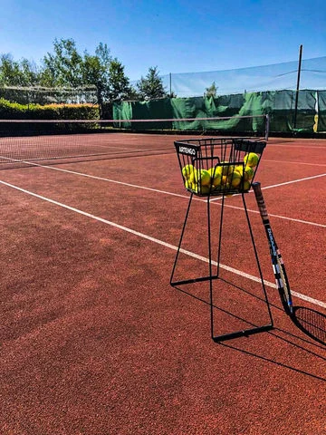 Tennis dvorek s košíkem míčů u sítě na kempu Hracholusky.