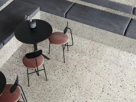Moderní interiér s dlažbou z terazzo a tmavými sedacími místy.