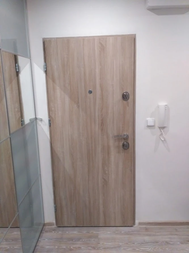 Modern dřevotřísková vstupní dveře do bytu s interfonem na zdi.