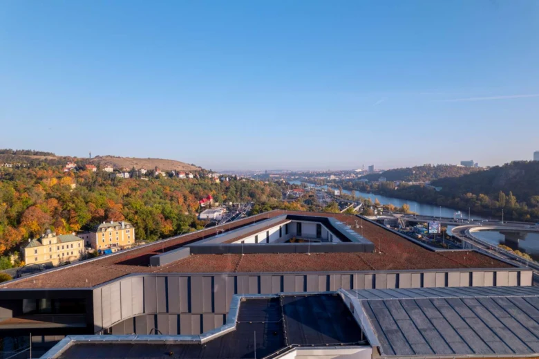 Moderní střechy v Barrandově s výhledem na řeku a les.