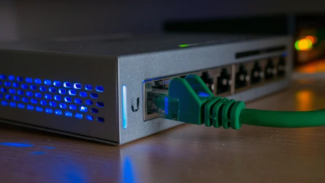 Zelený síťový kabel připojený k optickému rozvodnému zařízení.