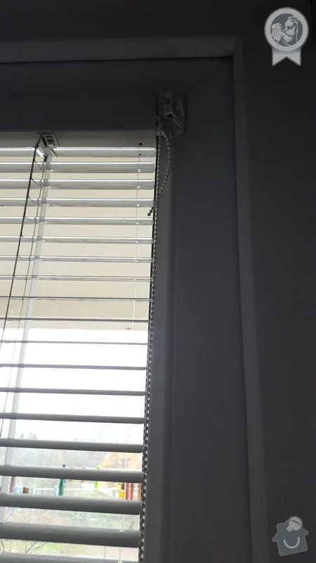 Detailní pohled na montáž bílých žaluzií v interiéru.