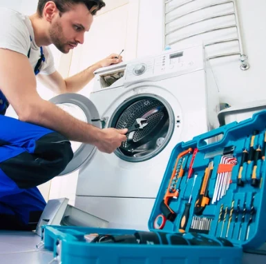 Technik opravuje pračku s otevřenou dveřmi a náradím.