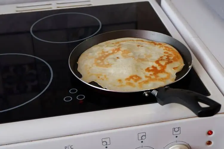 Pancák se vaří na indukční varné desce elektrického sporáku.