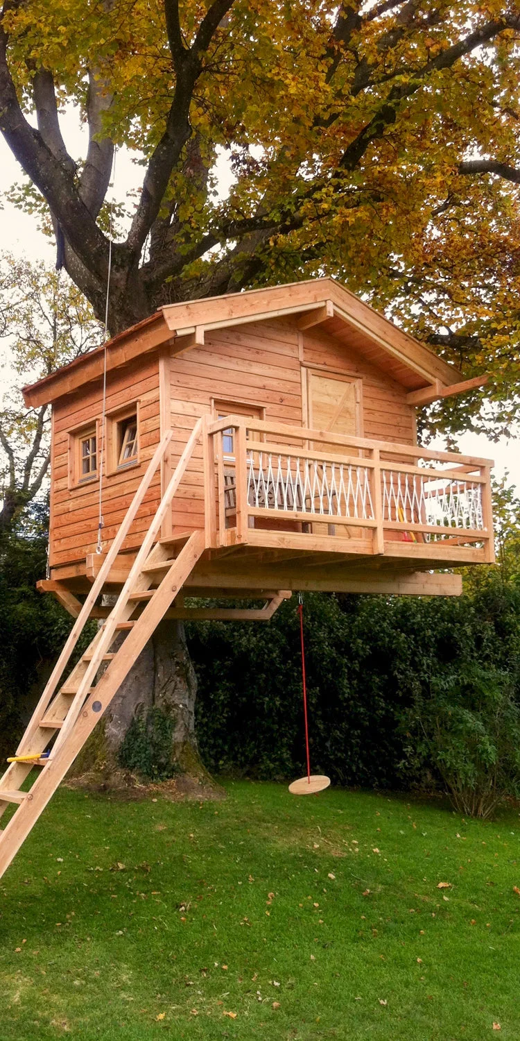 Dřevěný domek na stromě s balkonem a houpačkou
