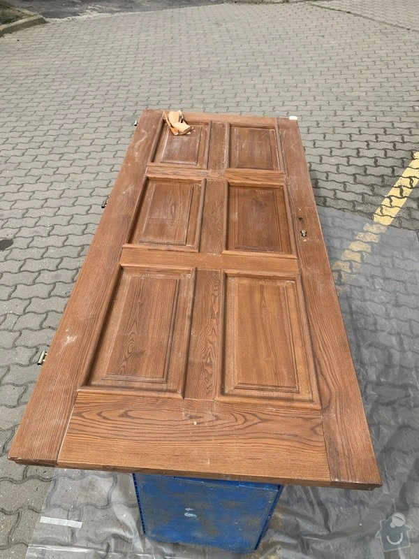 Dřevěná dveře připravené na restaurování leží venku.