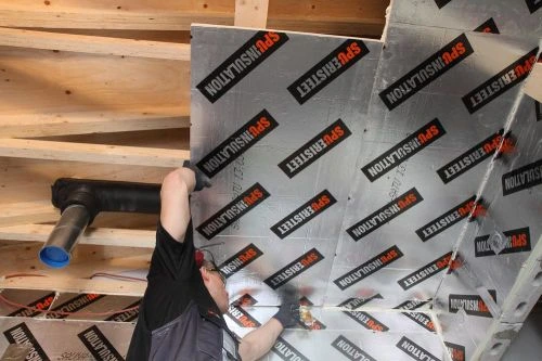 Instalace odrazivé izolační fólie do dřevěné konstrukce sauny.